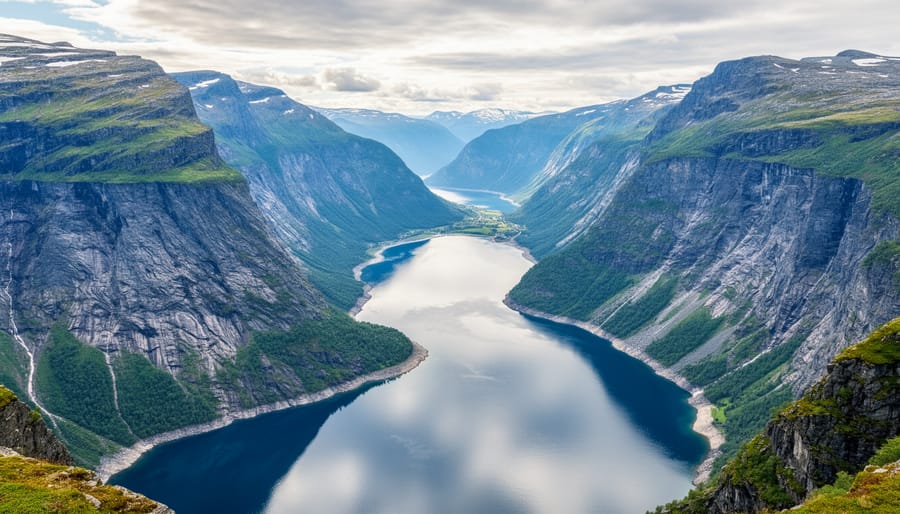 View from a Norwegian cliff over a fjord with steep rock walls, deep blue water, and a distant waterfall